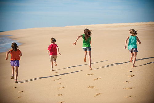 4 children playing and running on the beach