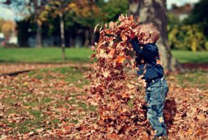 Child playing in pile of leaves, children's mental health